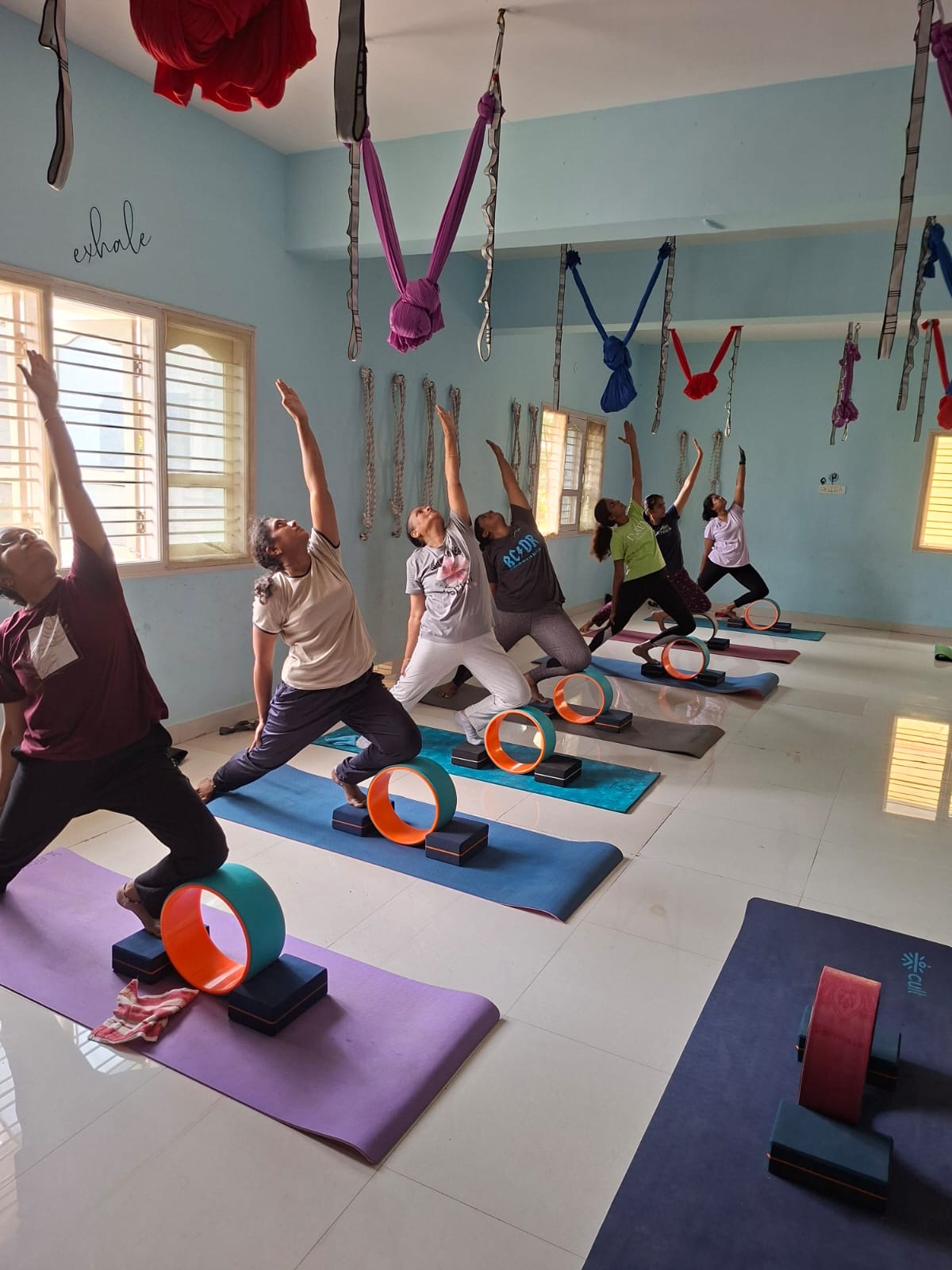 A standing yoga class with wheels and aerial silks in the blue-walled studio
